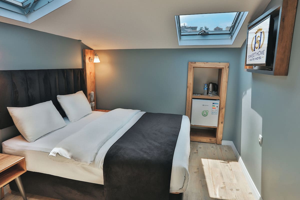 Ein Hotelzimmer mit Bett, Nachttisch, Lampe, Fernseher und einem Oberlicht.