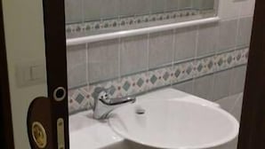 A bathroom with a white sink, a mirror above it, and a tiled floor. - Casa Rosy (Rome)