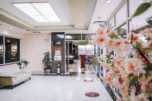 Un hall de hotel con mostrador de recepción, zona de estar y escalera que lleva a un piso superior.