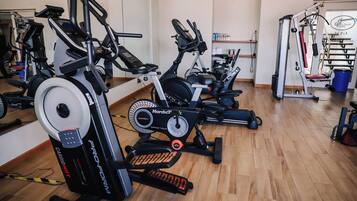 A gym with cardio machines, weight equipment, and a mirror wall.
