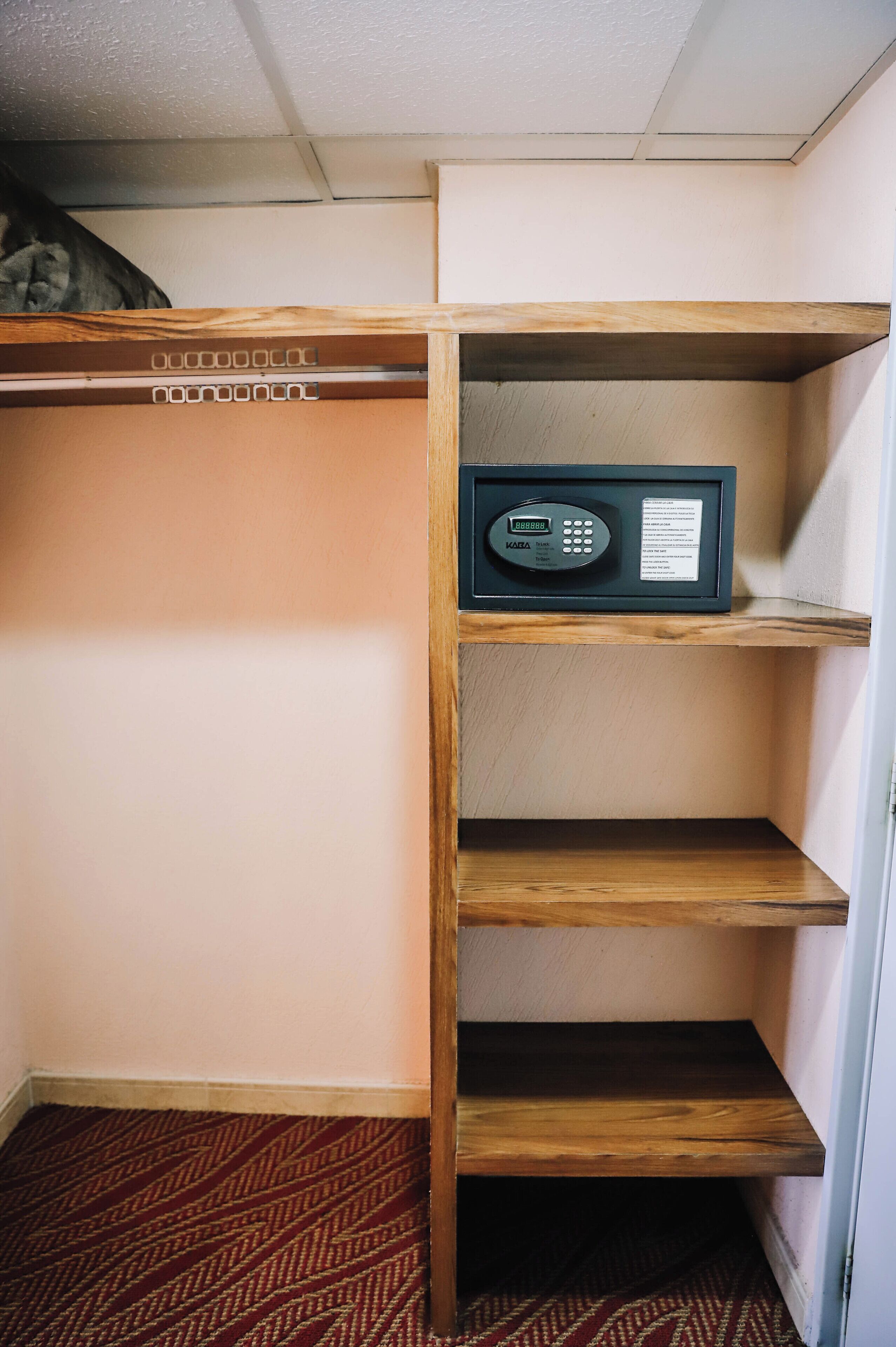 A storage closet with wooden shelves and a KABA electronic lock.