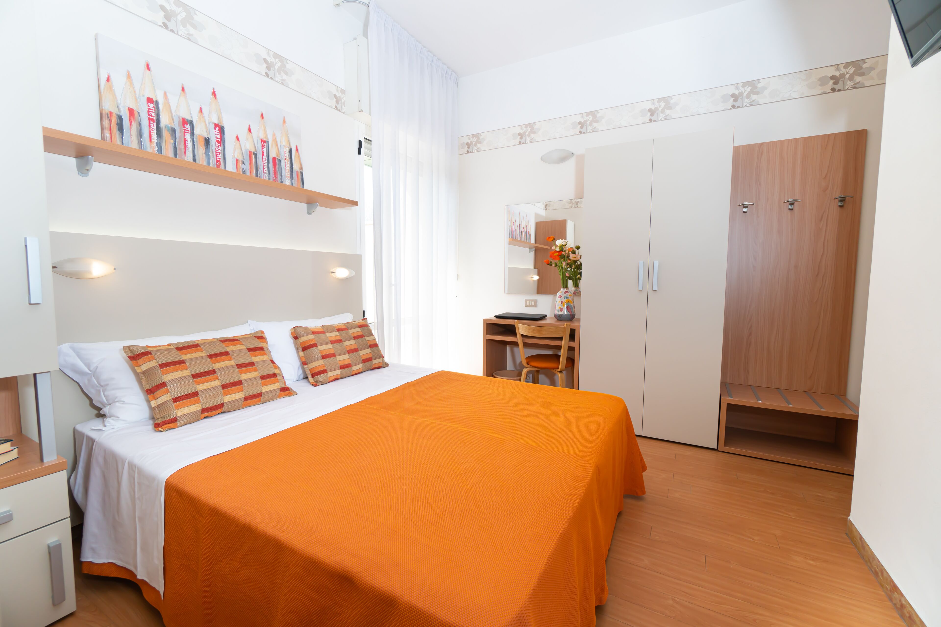 A bedroom with a bed, a desk, and a wardrobe.