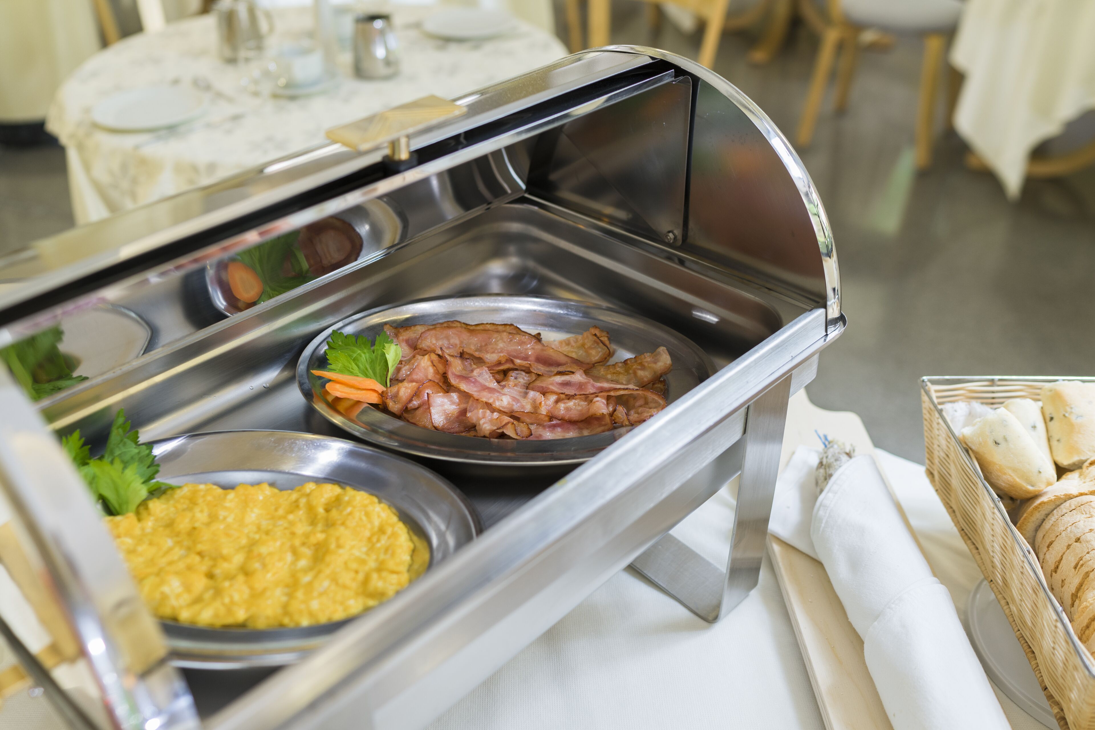 Un buffet proposant une variété de plats, notamment du bacon, des œufs brouillés et une salade.