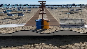A beach with a wooden walkway leading to beach umbrellas and chairs. - Hotel Sampaoli (Bellaria-Igea Marina)