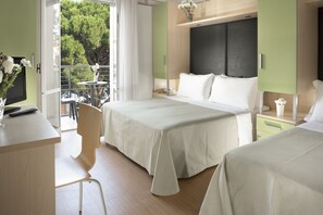 A hotel room with two beds, a desk, a chair, and a balcony with a view of trees. - Hotel Sampaoli (Bellaria-Igea Marina)