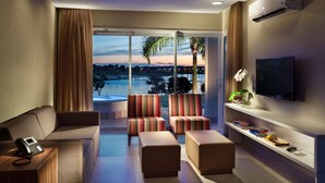 A modern hotel room with a sofa, armchairs, a TV, and a view of the outdoors. - Malai Manso Yacht Convention & Spa - All inclusive (Chapada dos Guimarães)