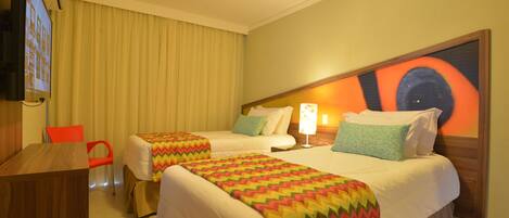 A hotel room with two single beds, a TV, a desk, and a chair.