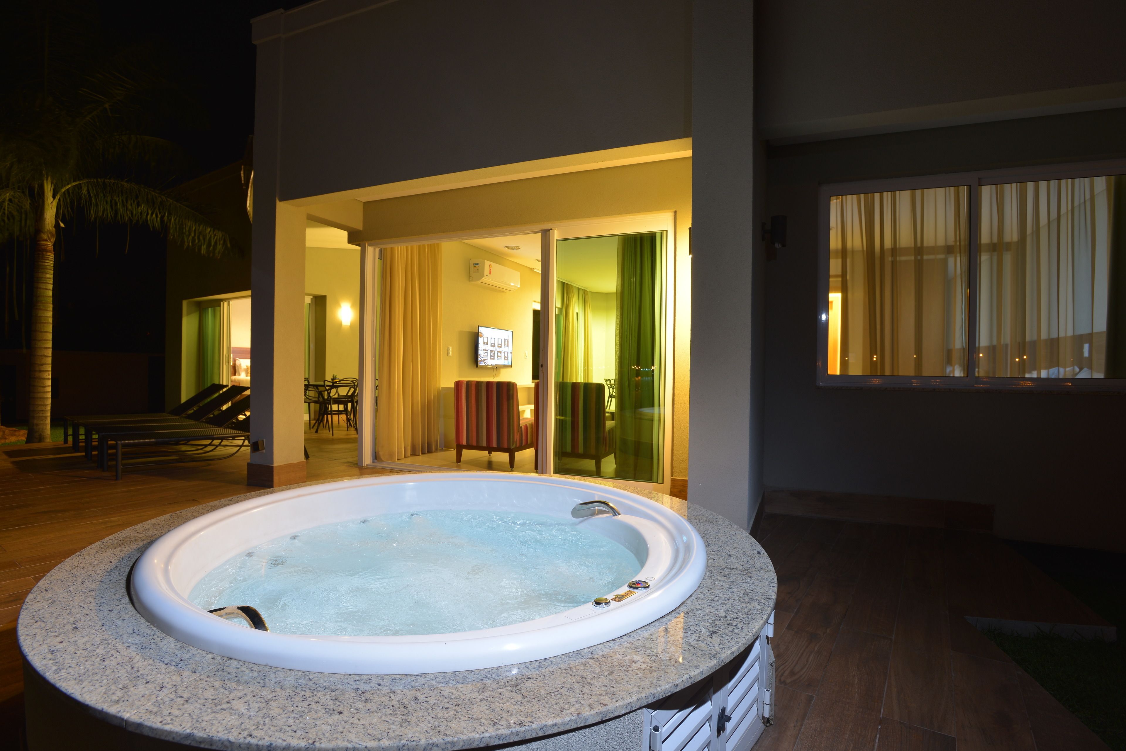 Un jacuzzi en un área exterior bien iluminada, con patio y mobiliario.