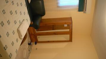 Una habitación con cama, cabecero de madera, ventana con persianas y aire acondicionado de pared.