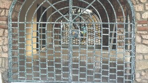 A stone building with a metal gate and a tiled entrance. - PC ENTREPRISES Hotel (Port-au-Prince)