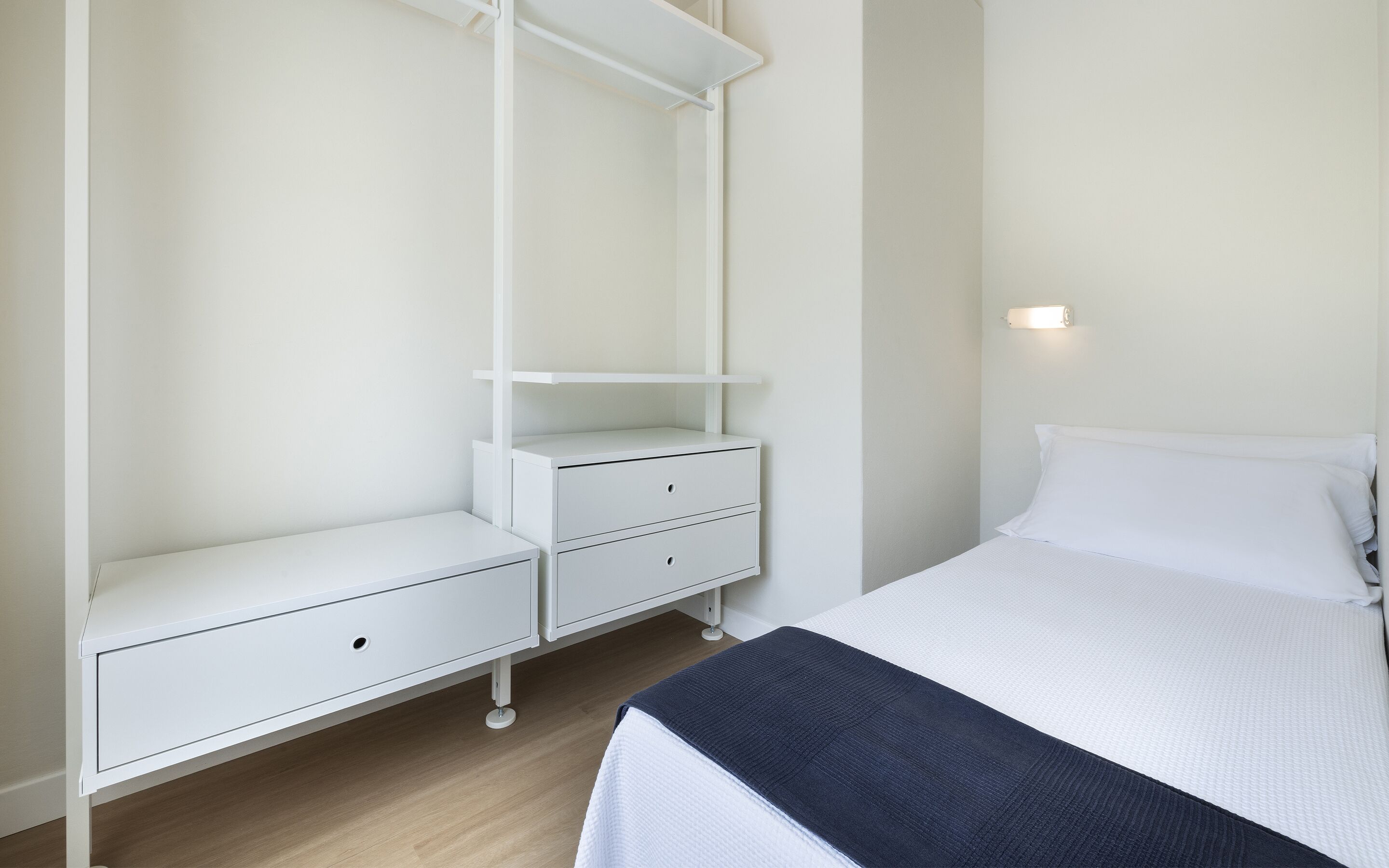 A bedroom with a bed, a nightstand, a dresser, and a wardrobe.