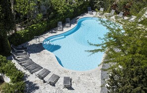 A swimming pool with a curved edge, surrounded by lounge chairs and a stone deck. - Hotel Buonafortuna (Bellaria-Igea Marina)