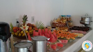 Un bufé con diferentes opciones de comida, incluyendo frutas, pan y pasteles.