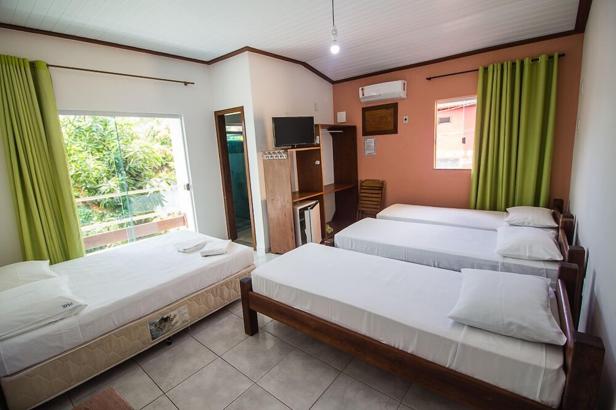Une chambre d’hôtel avec deux lits simples, une télévision, une armoire et une fenêtre avec des rideaux.