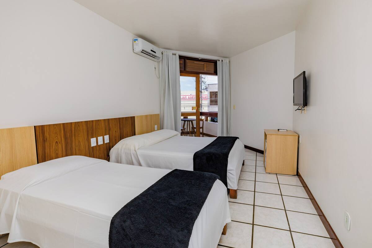 Une chambre d’hôtel avec deux lits, une télévision et une petite armoire en bois.