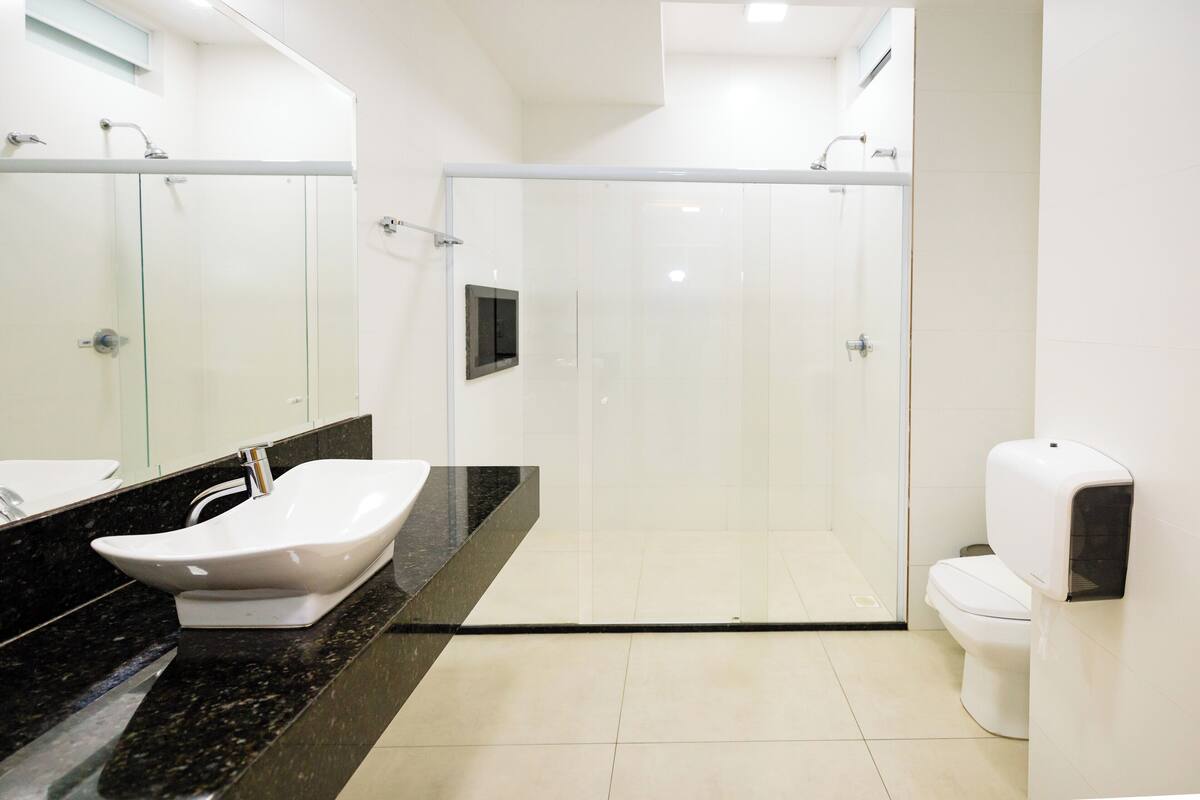 Une salle de bain moderne avec une douche à parois de verre, un lavabo blanc et des toilettes.