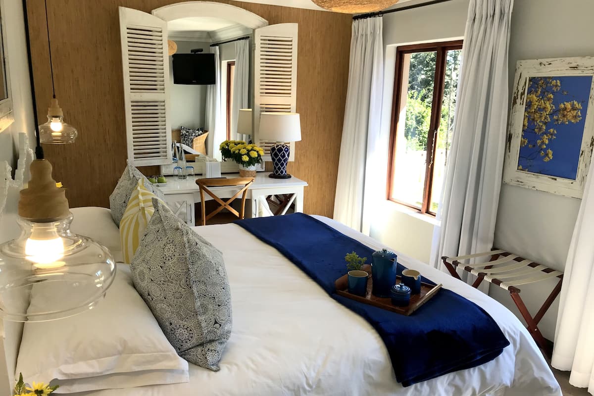 Un dormitorio con cama, mesita de noche, lámpara y ventana con cortinas.