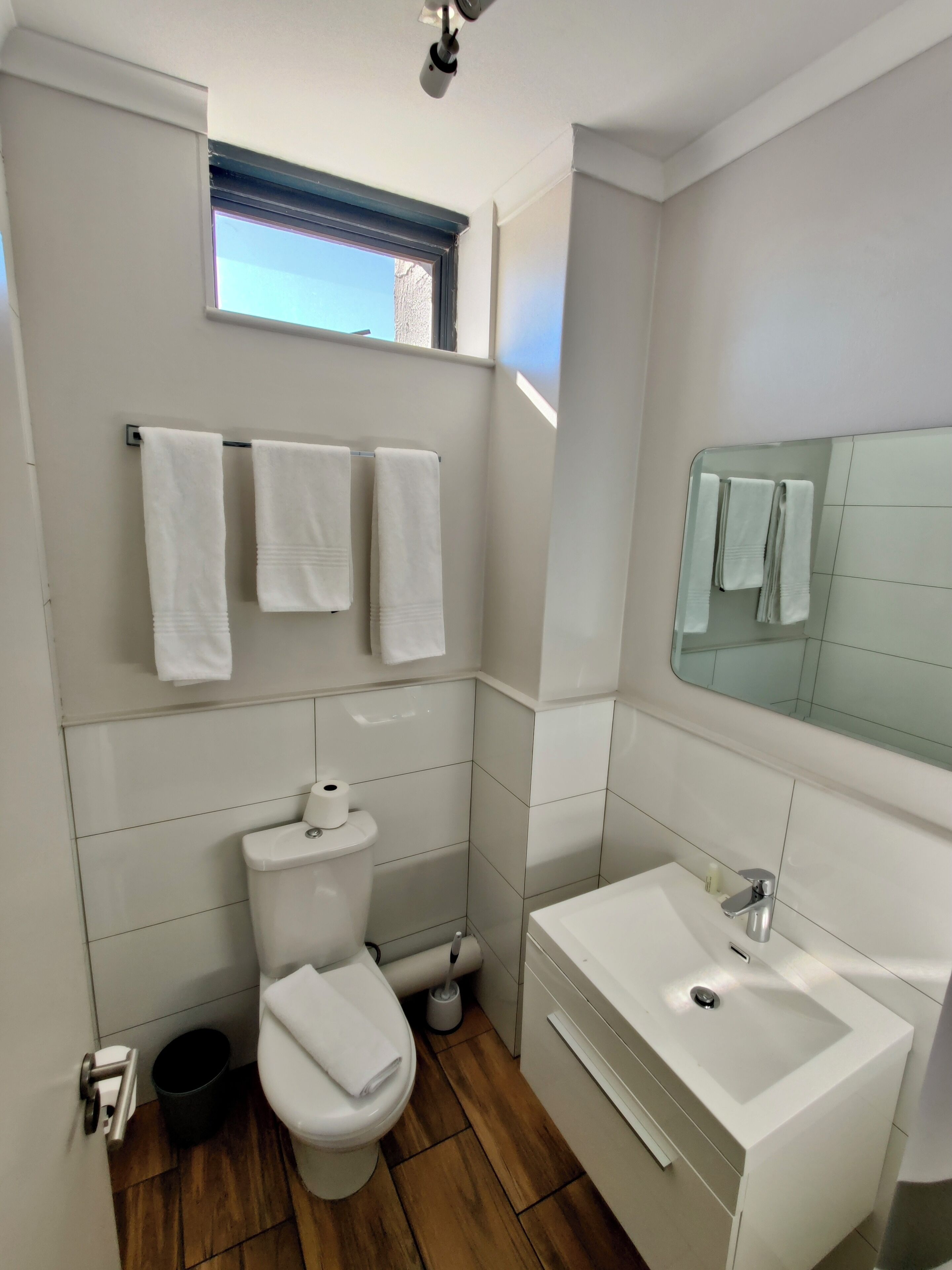 A modern bathroom with a toilet, sink, and a window above the toilet.