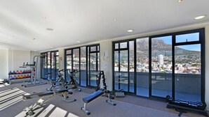 A gym with various exercise equipment and large windows offering a city view.