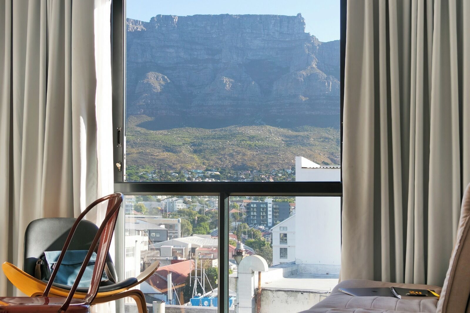 Habitación con un amplio ventanal que ofrece vistas a un paisaje montañoso y una ciudad.