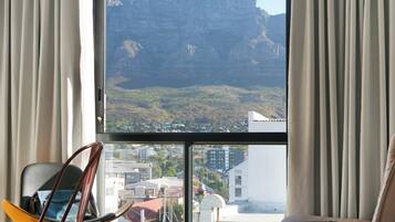 Habitación con un amplio ventanal que ofrece vistas a un paisaje montañoso y una ciudad.