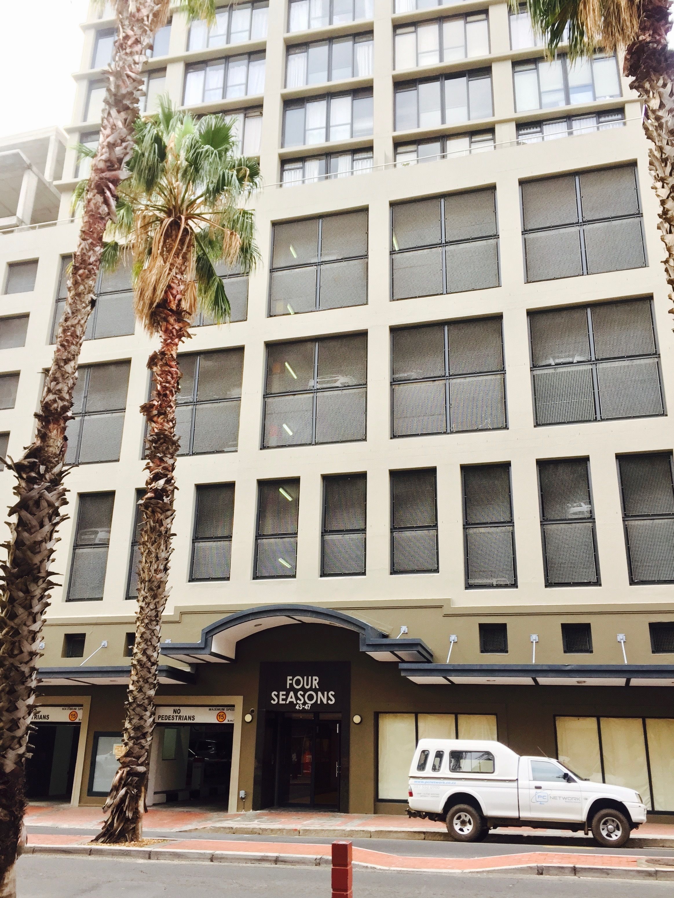 A multi-story hotel with a modern facade, featuring a prominent entrance labeled "FOUR SEASONS 43-47".