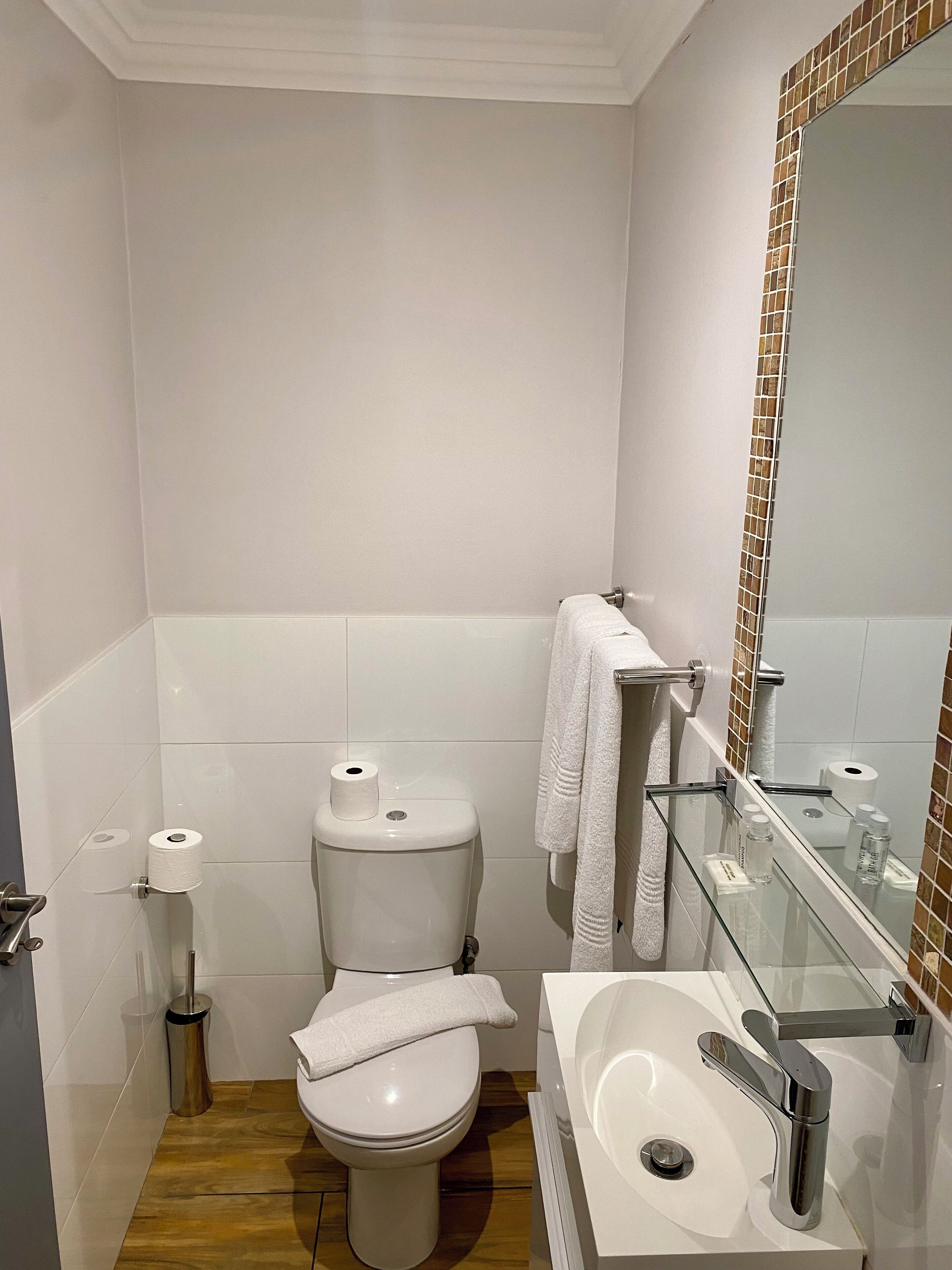 A modern bathroom with a toilet, sink, and mirror.