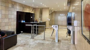 A reception area with a security desk, a lift, and a glass partition. - Urban Oasis at Perspectives (Cape Town)