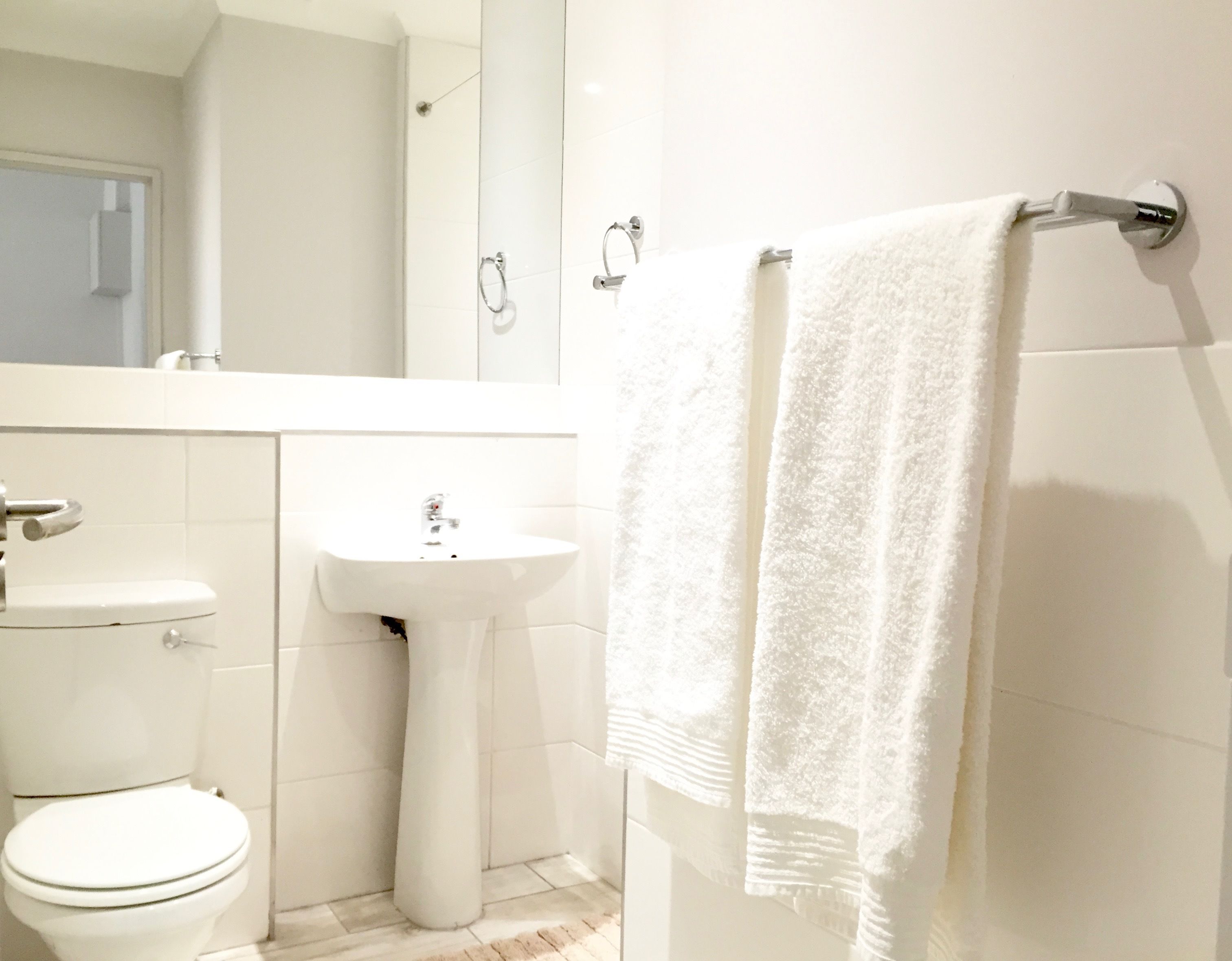 Une salle de bain équipée de toilettes, d’un lavabo et d’un porte-serviettes.