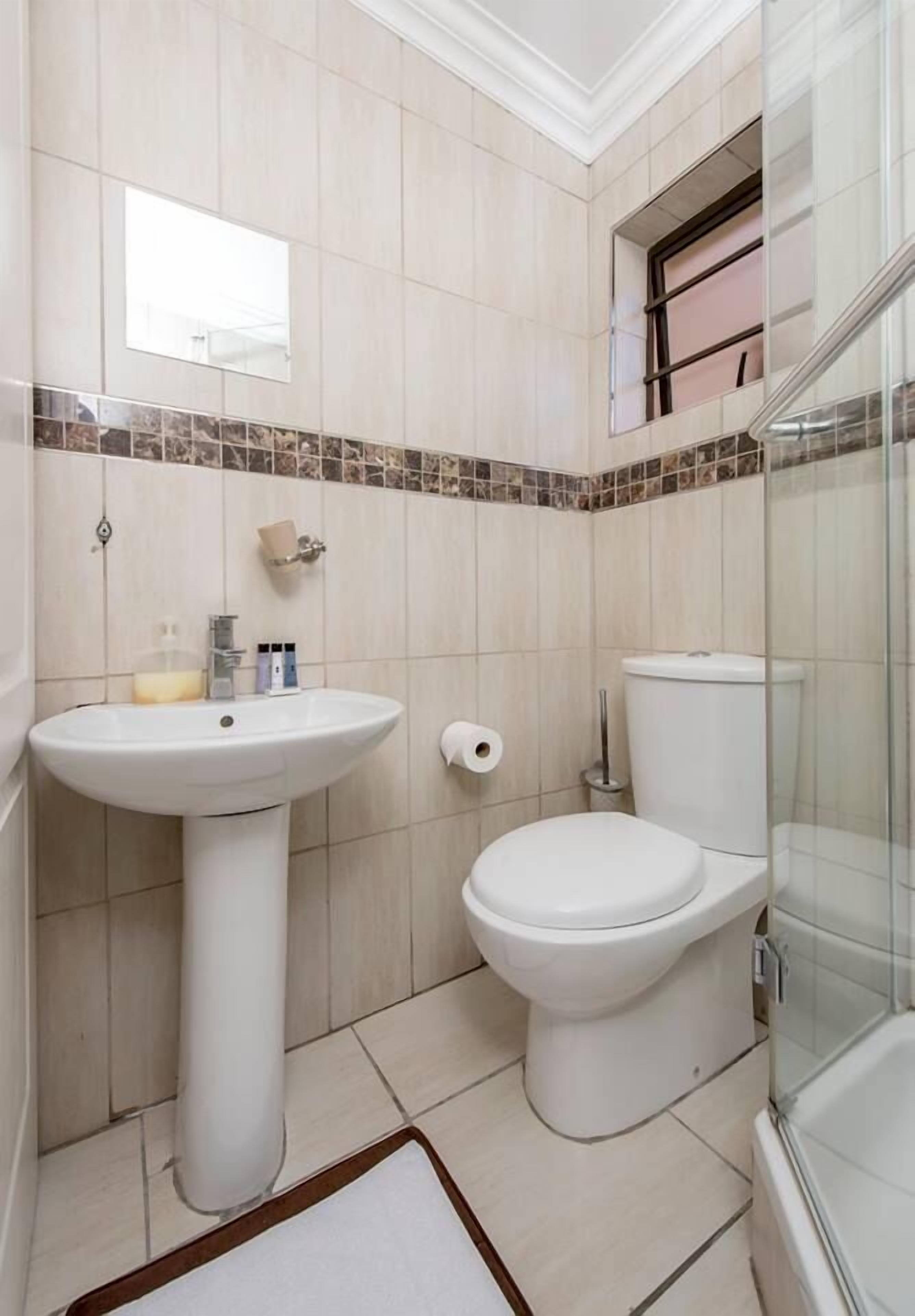 Casa de banho com lavatório assentado, sanita e cabine de duche em vidro.