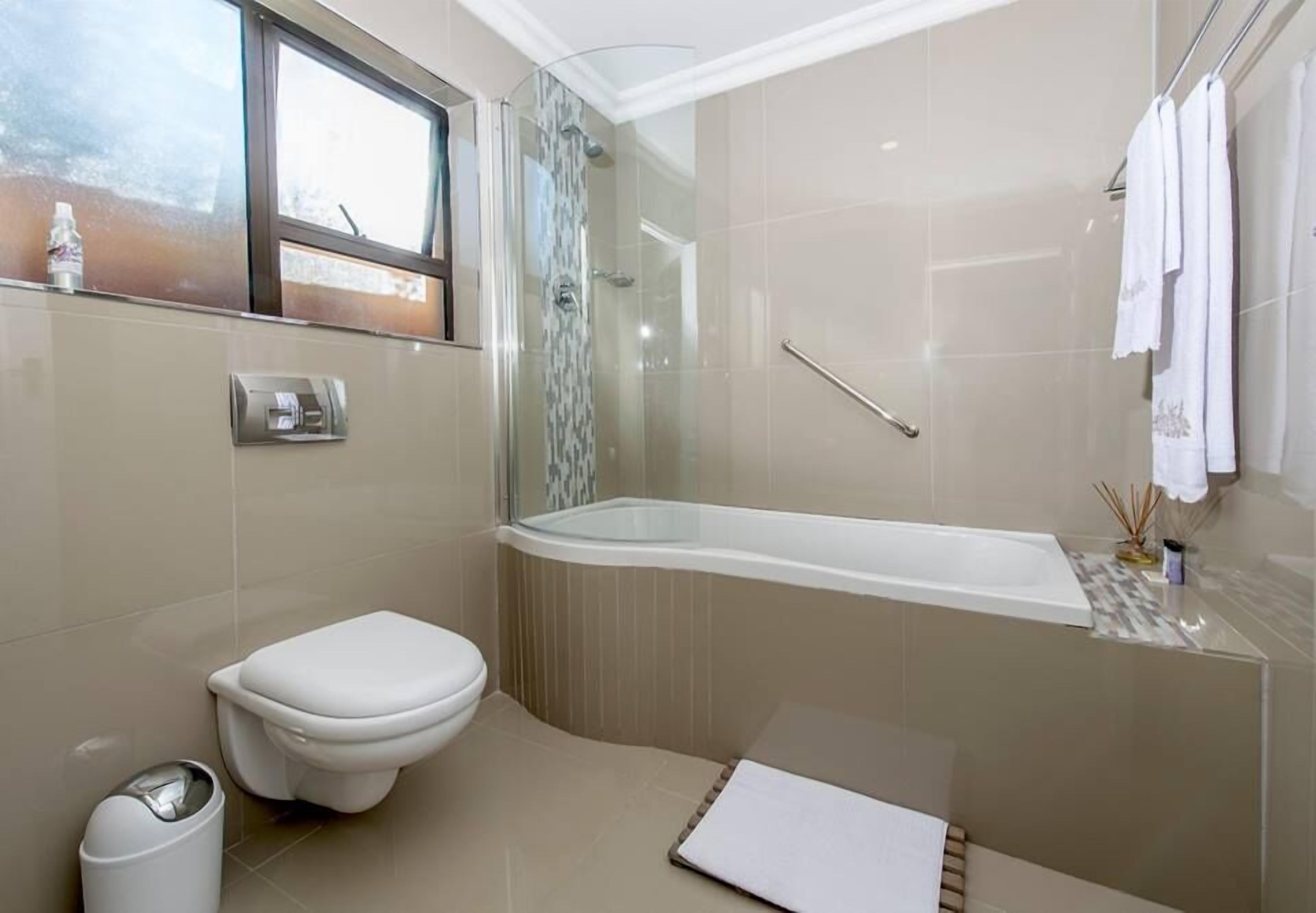 Une salle de bain moderne équipée de toilettes, d’une douche à parois de verre et d  ’une baignoire.