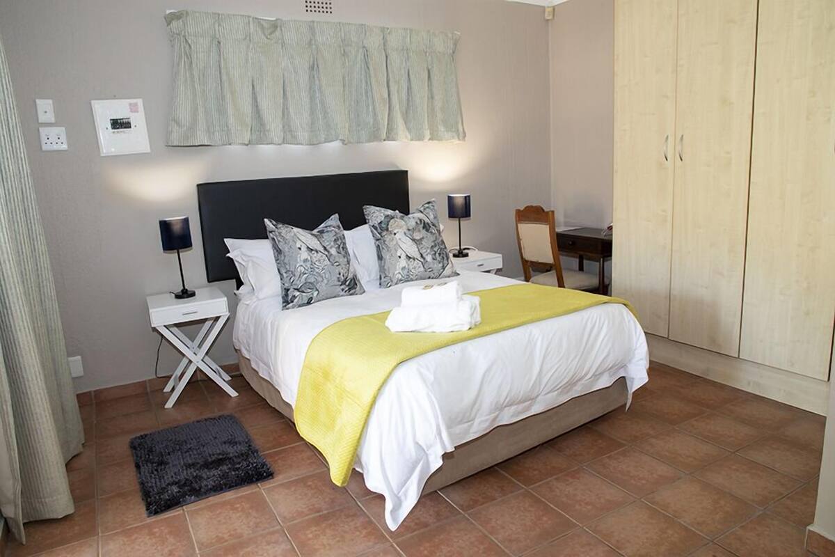 A bedroom with a bed, nightstands, a desk, and a wardrobe.