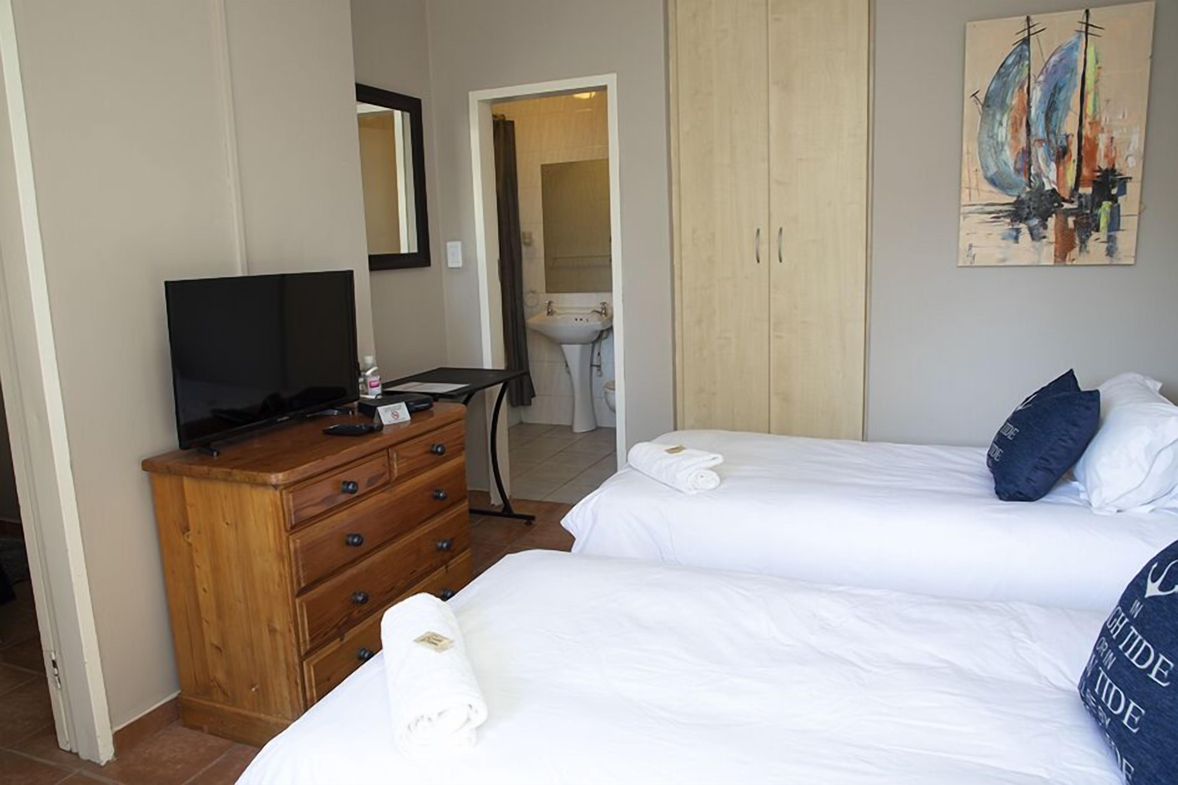 A hotel room with two beds, a wooden dresser, a television, and a painting on the wall.