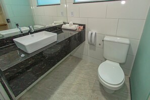 A modern bathroom with a rectangular sink, a toilet, and a towel rack. - Hotel Tuareg (Porto Seguro)