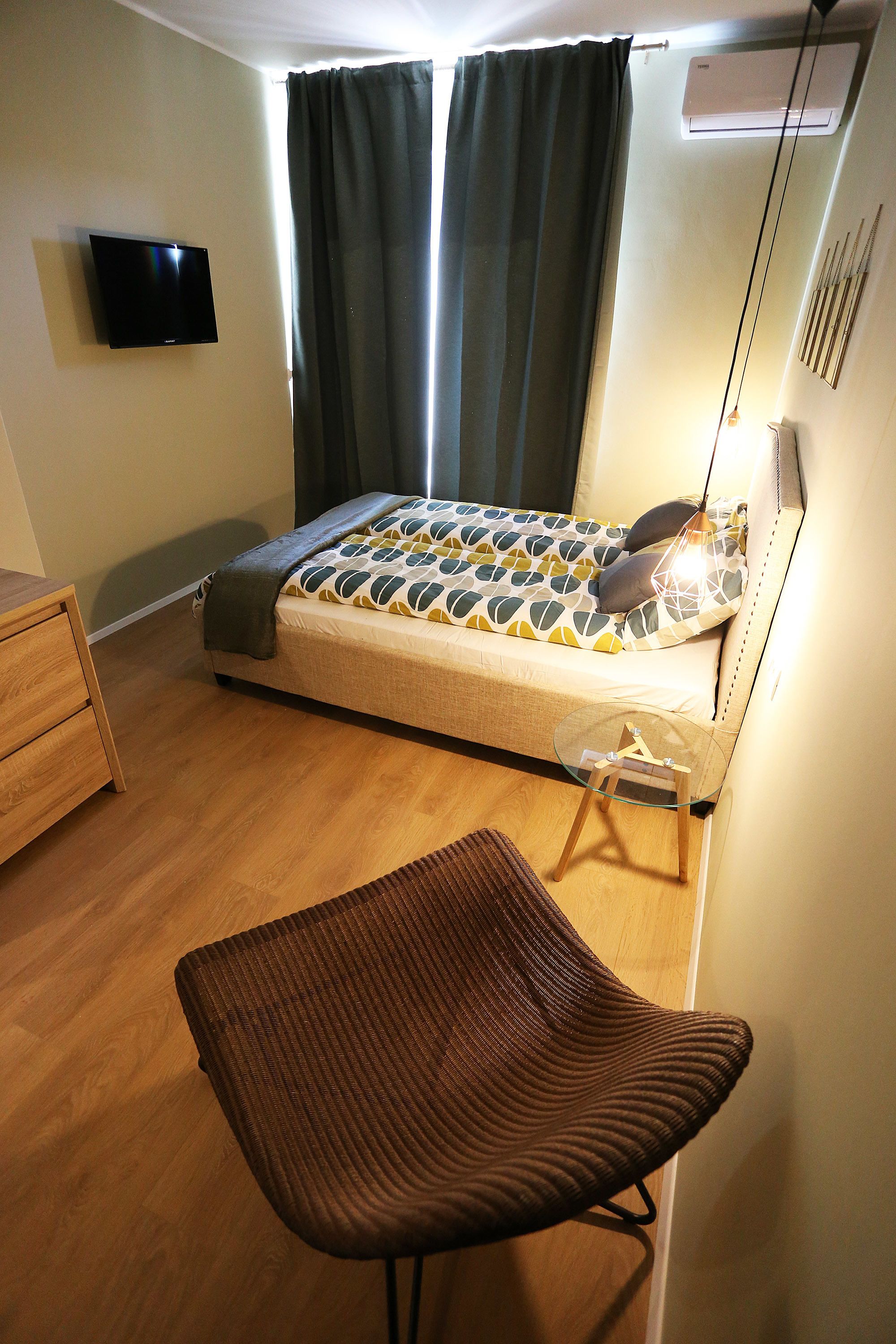A bedroom with a bed, a TV, a desk, and a chair.