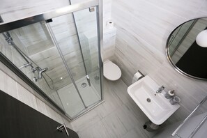 A modern bathroom with a glass-enclosed shower, a white toilet, and a sink with a mirror. - Prestige Rooms (Zadar)