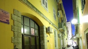 A narrow cobblestone street with yellow buildings, a stone entrance, and a sign for a restaurant. - Prestige Rooms (Zadar)