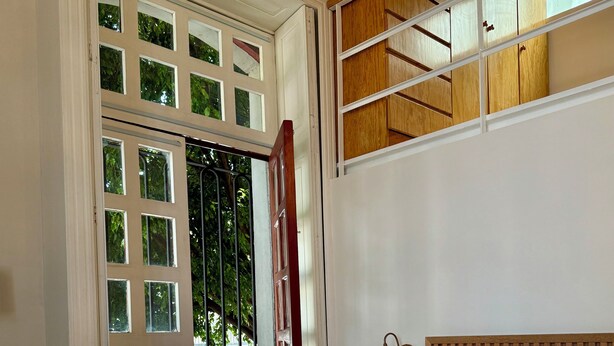 A bedroom with a bed, a nightstand, a lamp, and a window with a view of the outside. - Casa Moctezuma (Mexico City)