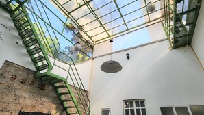 A high ceiling with a skylight, a green metal staircase, and a brick wall. - Casa Moctezuma (Mexico City)