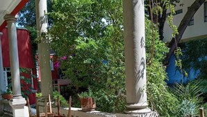 A covered outdoor area with a wooden chair and potted plants, surrounded by columns and a balustrade. - Casa Moctezuma (Mexico City)