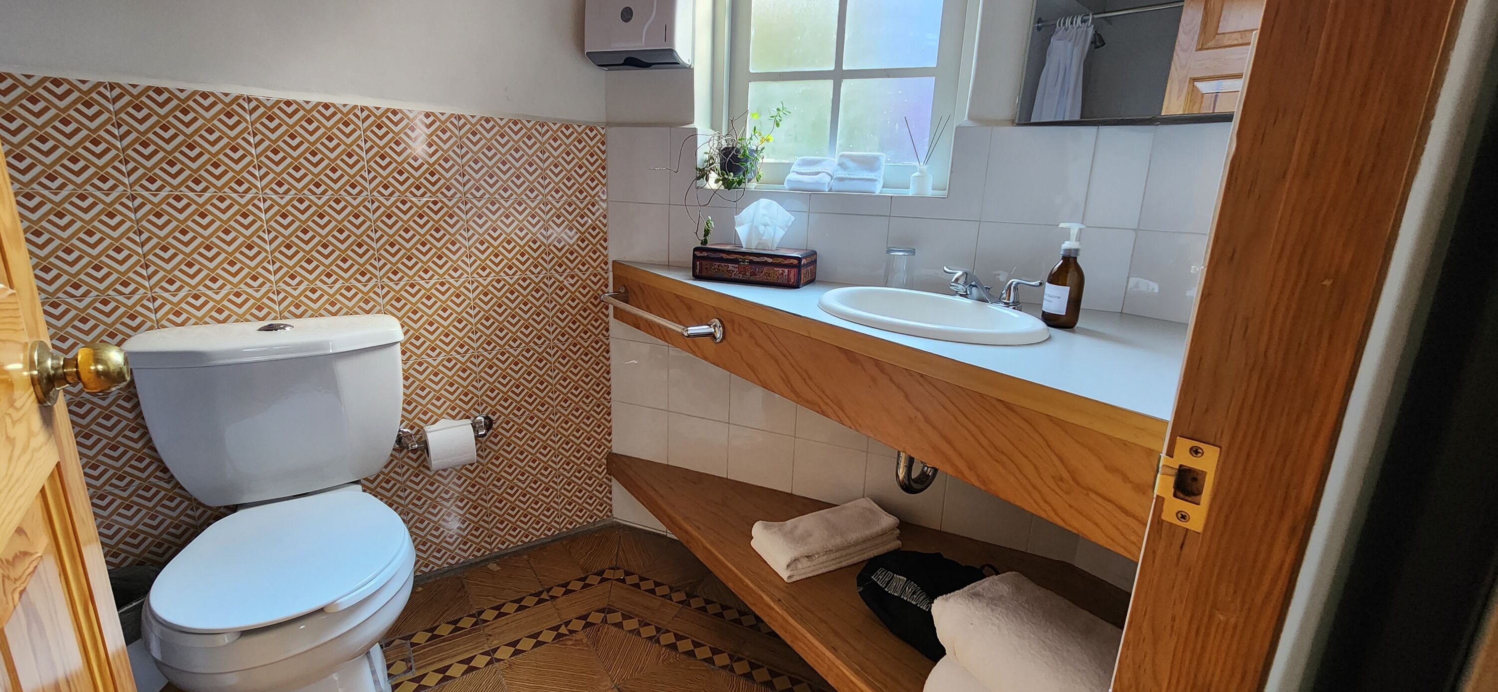 Une salle de bain avec des toilettes, un lavabo et une fenêtre située au-dessus du lavabo.