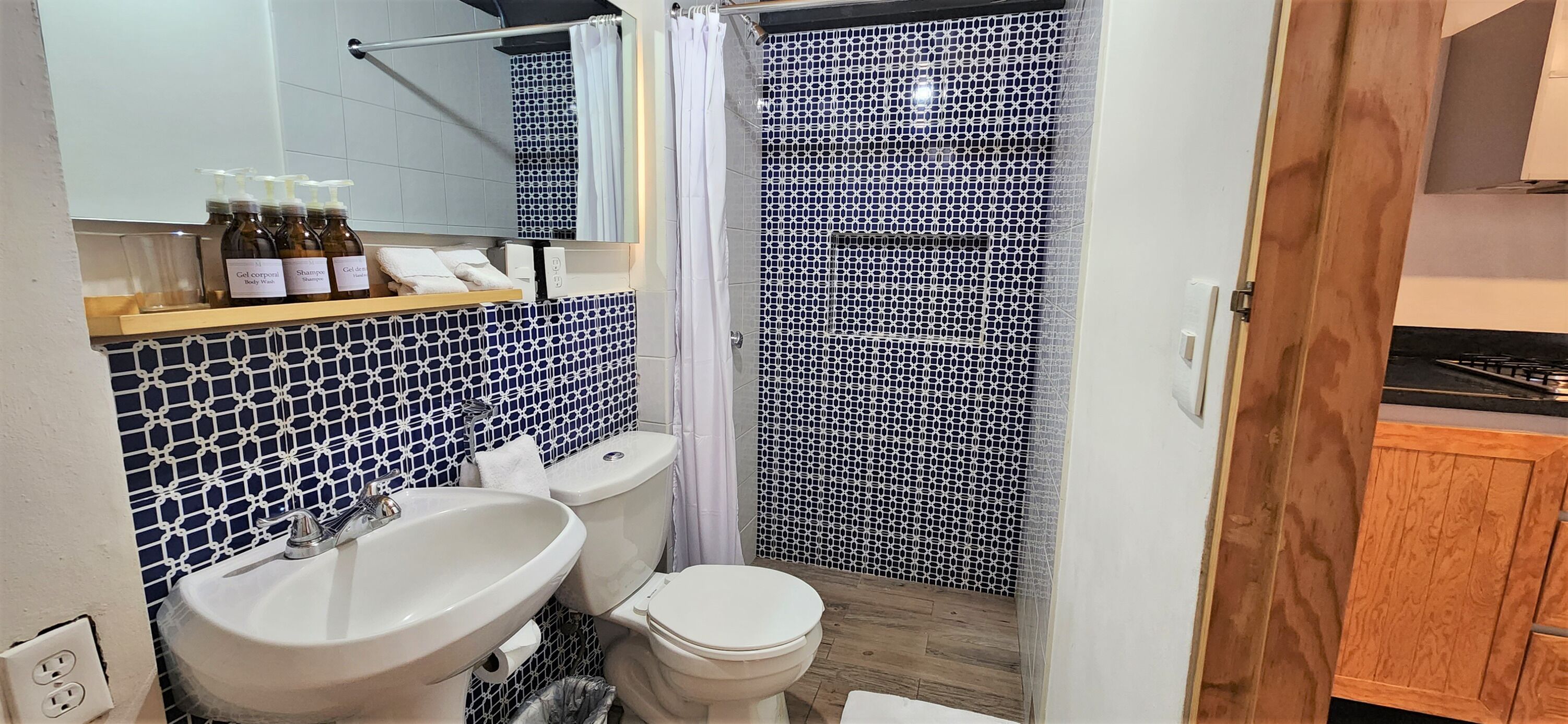 A bathroom with a white sink, a toilet, and a shower area with a patterned tile wall.