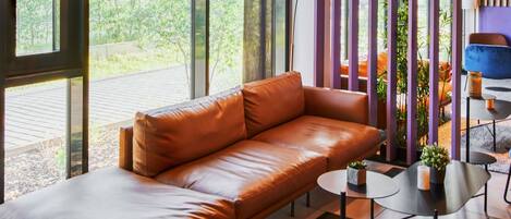 Una sala moderna con un sofá de cuero, una mesita redonda y una silla azul.