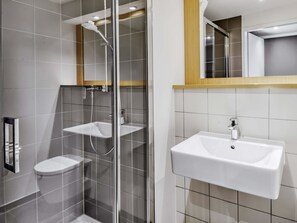A modern bathroom with a glass-enclosed shower, a toilet, and a sink.