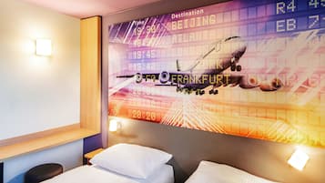 Habitación de hotel con una gran pantalla digital en la pared que muestra información de vuelos, incluyendo destinos como Pekín, Atlanta y Frankfurt.
