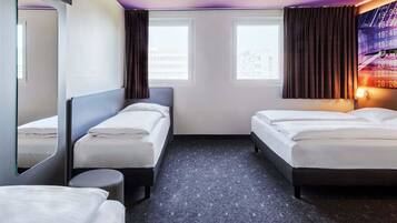 Ett hotellrum med två sängar, ett runt bord, en stor spegel och en väggklocka.