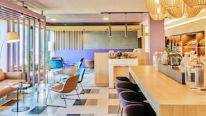A modern cafe with a checkered floor, a counter with bar stools, and a seating area with a sofa and chairs. - B&B Hotel Frankfurt-Airport (Frankfurt)