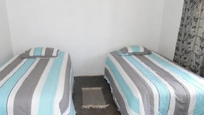 A small room with two single beds, each with striped bedding.