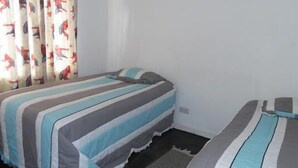 A bedroom with two beds, striped bedding, and curtains with a pattern.