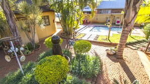 Un patio con piscina, palmeras y diversas plantas.